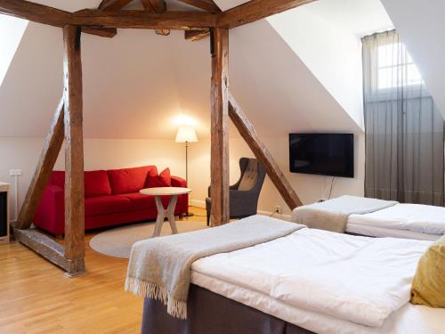 a room with two beds and a red couch at Elite Stora Hotellet Örebro in Örebro