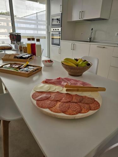 a table with a plate of meat and a bowl of fruit at Aura B&B in Pachino
