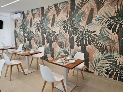 a restaurant with tables and chairs and a mural of palm trees at Aura B&B in Pachino