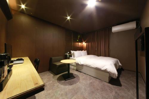 a bedroom with a bed and a table and a desk at Hotel Moon in Anyang