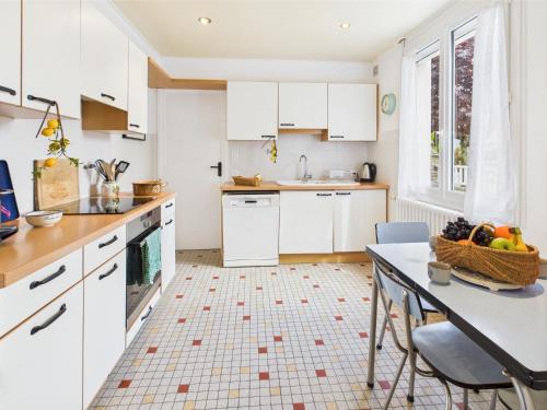 a kitchen with white cabinets and a table with a basket of fruit at -SUZANNE- Maison de charme au coeur de Nevez in Névez