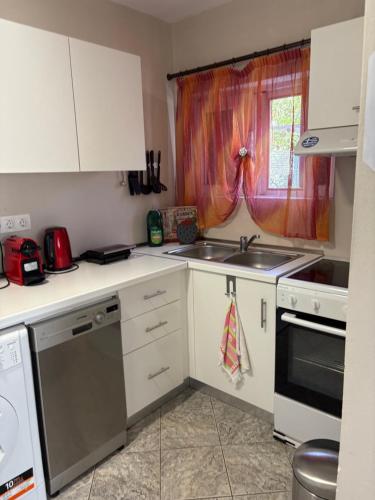 a kitchen with white cabinets and a sink and a window at MEIMETIS GREEN HOUSE in Neapolis