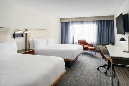 a hotel room with two beds and a desk at Courtyard Chicago Midway Airport in Bedford Park