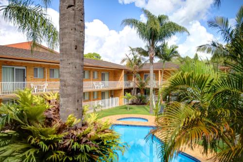 an exterior view of a resort with a swimming pool and palm trees at Beachpark Apartments Coffs Harbour in Coffs Harbour