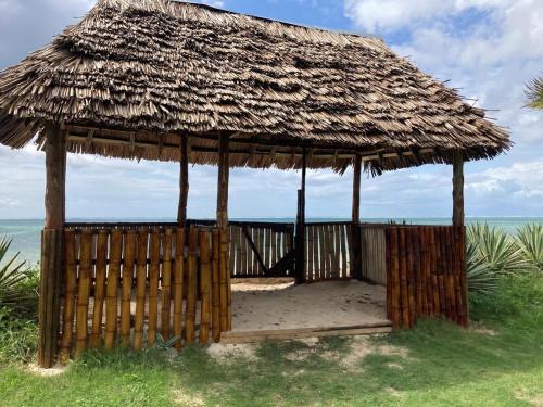 a hut with a straw roof on the beach at Ahadi Beachfront by YourHost 2 bedroom Kilifi in Mombasa