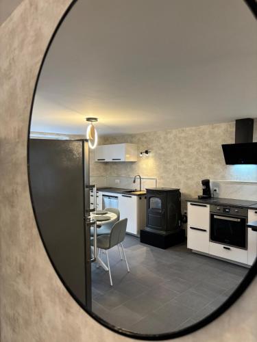 un miroir reflétant une cuisine avec une table et une cuisinière dans l'établissement Le repos du voyageur, à Rolampont