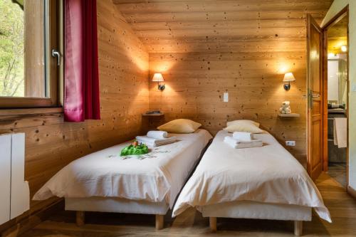 two beds in a room with wooden walls at Chalet Snow Mountain in Le Bettaix