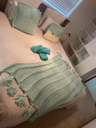 a bed with a green blanket and two pillows at Knysna's Rest in Brenton-on-Sea
