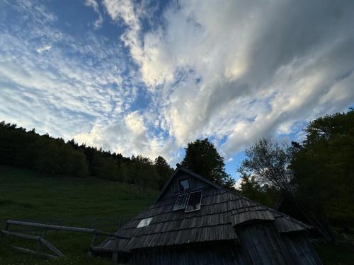 an old barn in a field under a cloudy sky at Mountain Lodge Suška Koča in Stahovica