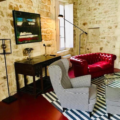 un salon avec un canapé rouge et deux chaises dans l'établissement Belle maison historique, à Arles