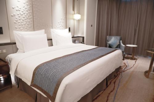 a large white bed in a hotel room at Wyndham Qingdao l Free Fixed-Time Shuttle Service Between Hotel and Airport & North Railway Station l Outdoor Children's Amusement Park l 1-Hour Play Snooker or Table Tennis in Qingdao