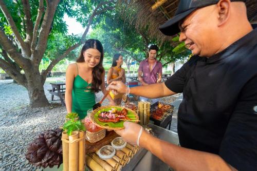 a man handing a woman a plate of food at Astoria Palawan in Puerto Princesa City