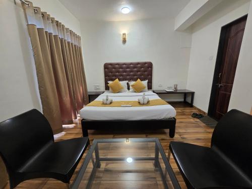 a bedroom with a bed and two chairs and a table at Hotel Vyankatesh & Pure Veg Restaurant in Mahabaleshwar
