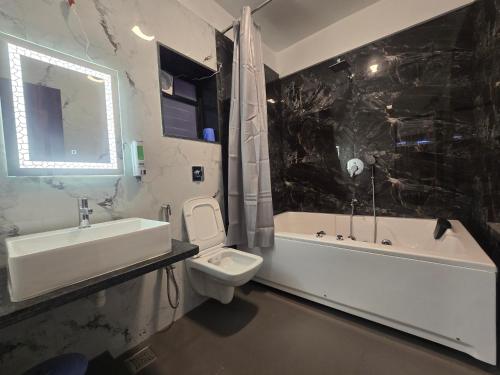 a bathroom with a sink and a toilet and a bath tub at Hotel Vyankatesh & Pure Veg Restaurant in Mahabaleshwar
