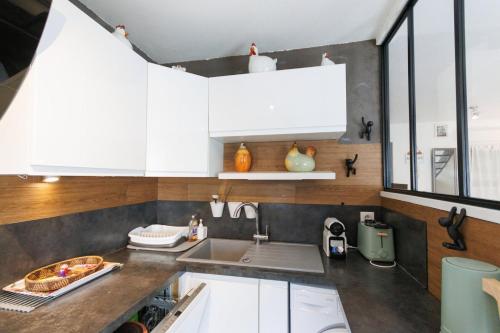 une cuisine avec des armoires blanches et un évier dans l'établissement Le Duplex Preize chez Stéphane et Sabrina, à Troyes