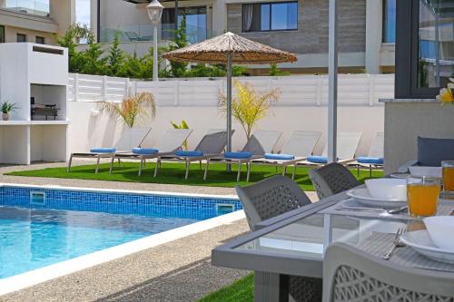 un patio con tavolo e sedie accanto alla piscina di Villa Violeta - 3bed Bungalow large pool a Protaras