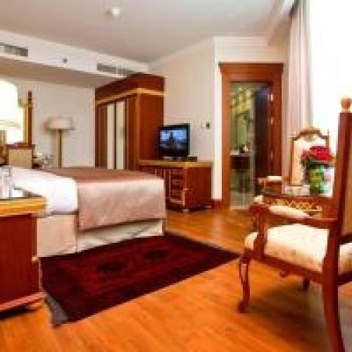 a bedroom with a bed and a tv and a chair at Dancenter Luxury Holiday International Dubai in Dubai
