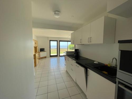 une cuisine avec des armoires blanches et un sol carrelé dans l'établissement appartement pied dans l'eau Bonne source, à Pornichet