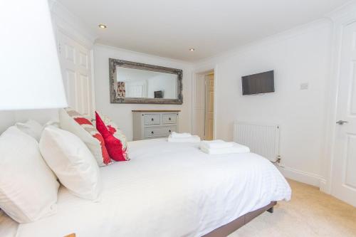 a white bedroom with a large white bed with red pillows at Raleigh by Pureserviced in Plymouth