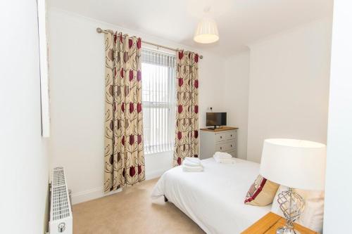 a bedroom with a bed and a lamp and a window at Raleigh by Pureserviced in Plymouth