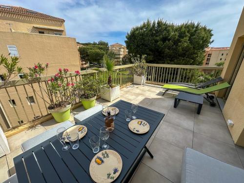 a blue table with wine glasses on a balcony at Genévriers - T2 - Terrasse - piscine - Parking in Six-Fours-les-Plages