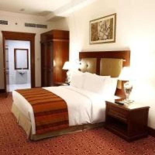 a hotel room with a large bed and a table at Dancenter Luxury Holiday International Dubai in Dubai