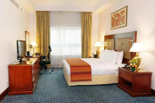 a hotel room with a large bed and a desk at Dancenter Luxury Holiday International Dubai in Dubai