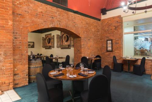 a restaurant with a brick wall and tables and chairs at Scenic Hotel Southern Cross in Dunedin