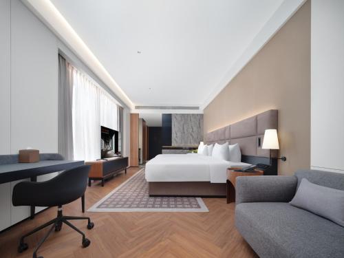 a bedroom with a bed and a desk and a couch at Intercity Hotel South Central Taiyuan in Taiyuan