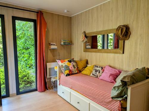 Zimmer mit einem Bett mit Kissen und einem Spiegel in der Unterkunft Studio en bois, confort et modernité in Saint-Brevin-les-Pins
