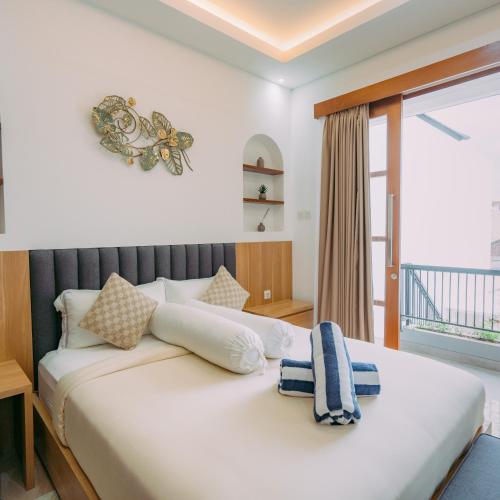 a bedroom with a large white bed with a window at The Lavana Nakula Villa Kuta Sunset in Kuta