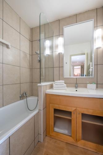 une salle de bain avec une baignoire, un lavabo et un miroir dans l'établissement Résidence Pierre & Vacances La Forêt, à Flaine