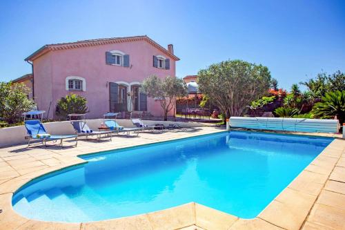 une piscine devant une maison rose avec des chaises bleues dans l'établissement Villa Les Capucines by Villa Plus, à La Garde
