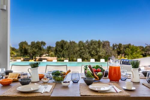 a wooden table with food on it with a pool at Villa Libe by Perle di Puglia in Specchiolla 