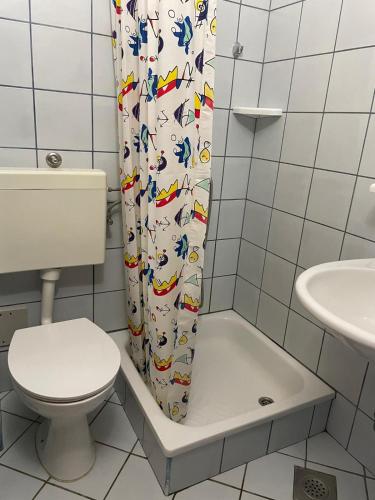 a bathroom with a toilet and a shower curtain at Apartments Vozab in Pag