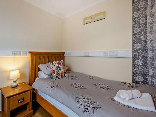 a bedroom with a bed and a night stand with a lamp at 5 bed in Brynteg 75907 in Llanwenog