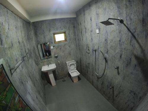 a bathroom with a shower and a toilet and a sink at Kirindioya Village Safari Lodge in Tanamalwila