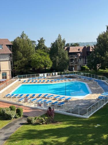 Elle offre une vue sur la grande piscine bordée de chaises. dans l'établissement Petit Golf résidence privée piscine chauffée, à Deauville