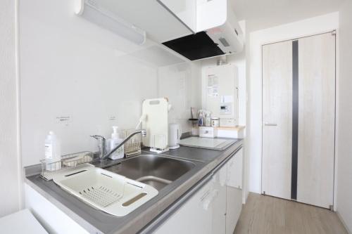 a white kitchen with a sink and a refrigerator at Comfort Boutique Room in Tokyo