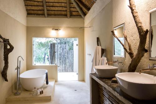 a bathroom with two sinks and a large window at Ezulwini Game Lodges in Balule Game Reserve