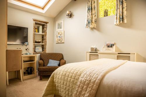 a bedroom with a bed and a chair and a television at Shibden Mill Inn in Halifax