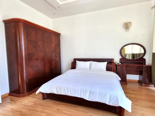 a bedroom with a bed with a wooden headboard and a mirror at Top Hill Halong in Ha Long