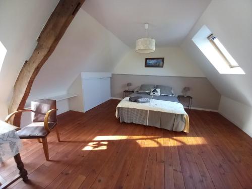 une chambre avec un lit et une chaise dans un grenier dans l'établissement Maison cocon près de la mer, à La Turballe