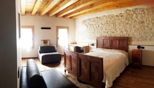 a bedroom with a bed and a couch and a chair at Casa Tormena in Valdobbiadene