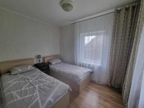 a bedroom with two beds and a window at Nakvynė Akmenėje -Pušyno pašonėje- in Akmenė