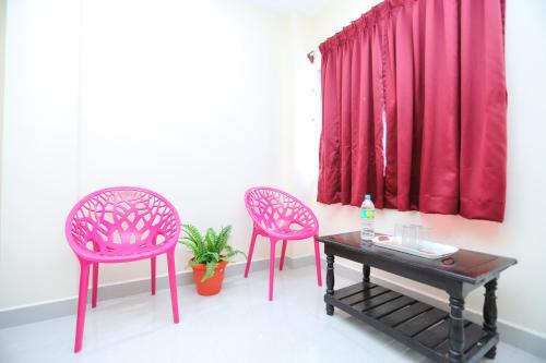 two pink chairs and a table in front of a window at Royal Dreams Beach View in Puducherry