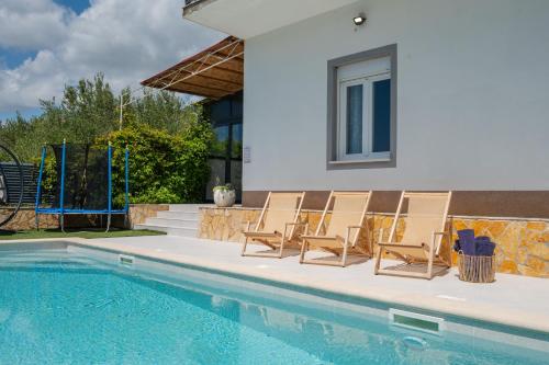a group of chairs sitting next to a swimming pool at Holiday house Kristina with heated Pool, 10pax in Tugare