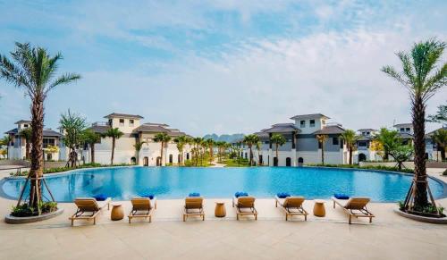 a pool at a resort with chairs and palm trees at Dragon Villa 3 Bedroom - Sonasea Vân Đồn Harbor City in Thâm Câu