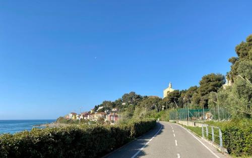 eine leere Straße neben dem Meer auf einem Hügel in der Unterkunft Le case di Sara - Green Palm in Arma di Taggia