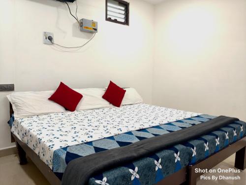 a bed with red pillows on it in a room at Annamaiah Guest House & Homestay - Tirupati - Home Food Service in Tirupati